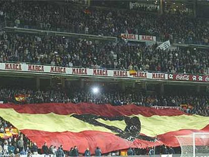 Una gran bandera de España, con un crespón negro, cubre las gradas del estadio Bernabéu.