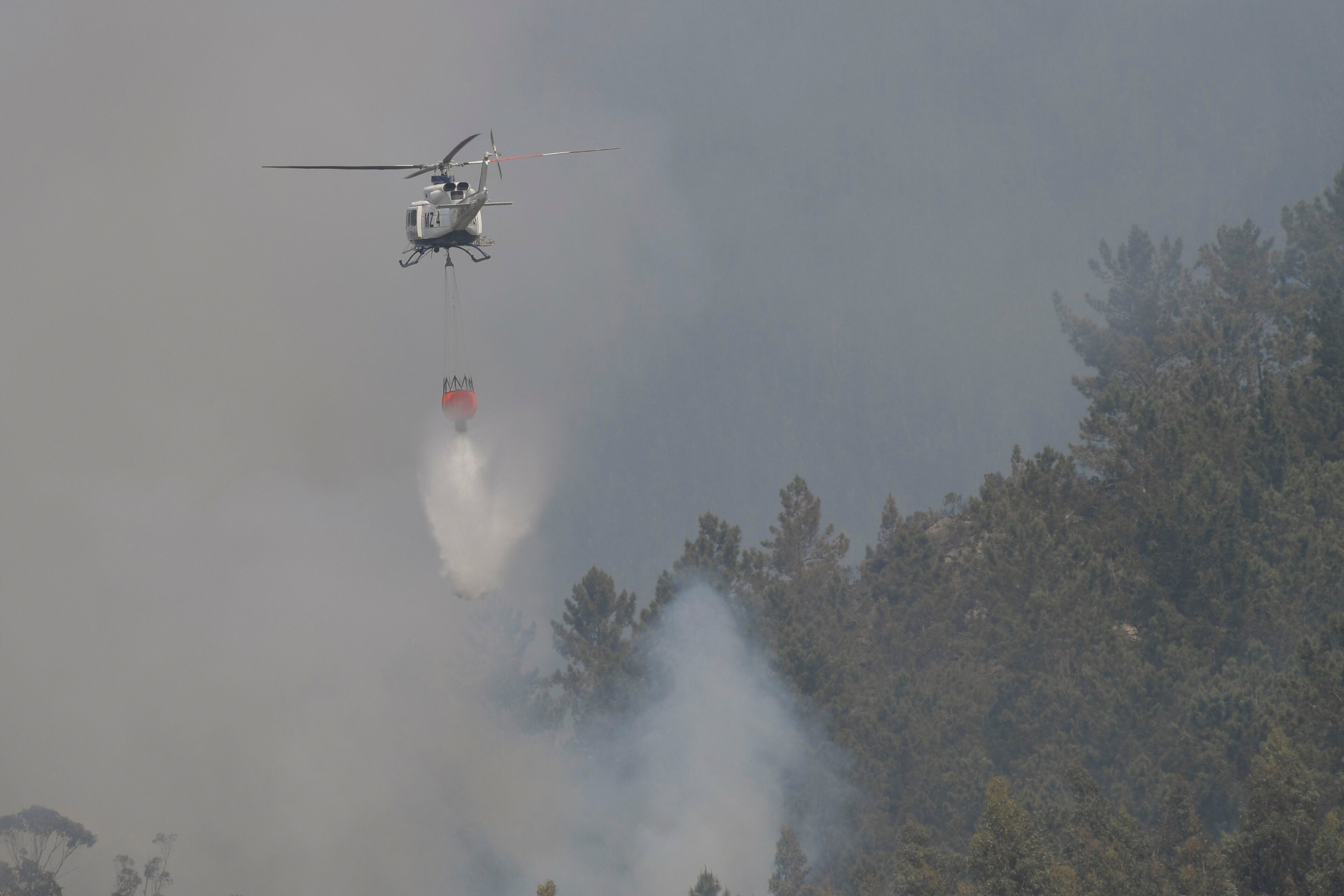 Un helicóptero participaba el domingo en las tareas de extinción de un incendio en Las Regueras, en las cercanías de Oviedo.