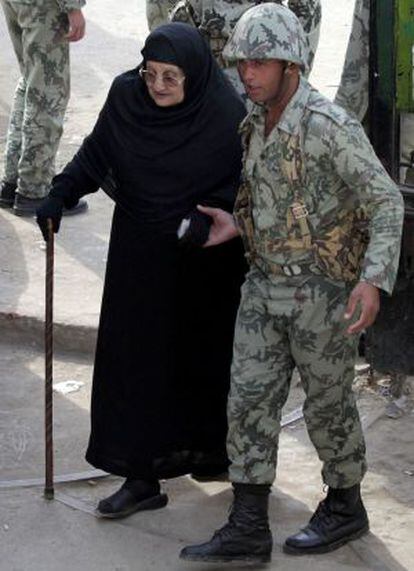 Un soldado asiste a una mujer mayor a acudir a un centro de votación en Giza