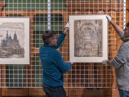 Dos operarios del MNAC, con los dos dibujos  de Gaudí que acaban de ingresar en el museo. 