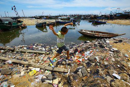 Un niño juega entre la basura en una playa de la provincia de Hainan.
