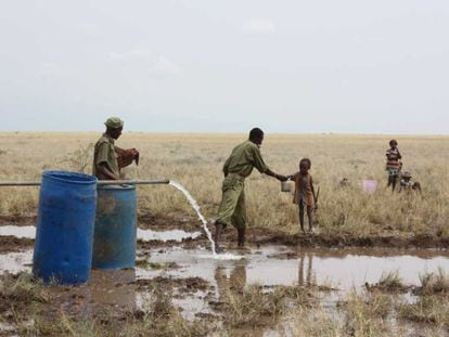 Un policía keniata da agua potable a un niño sediento en el pozo de la villa de Lotikipi.
