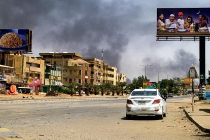 El humo se elevaba al fondo mientras un coche circulaba el domingo por una calle casi desierta en Jartum.