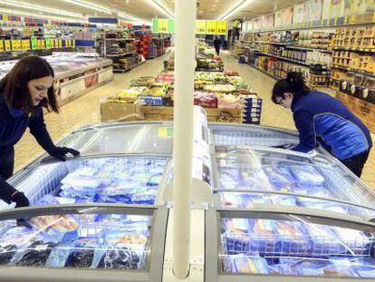 Dos empleadas reponen las neveras de un supermercado Lidl en Madrid.