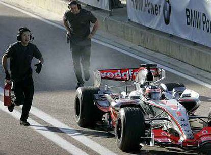 Un asistente corre con el extintor hacia el coche de Fernando Alonso.