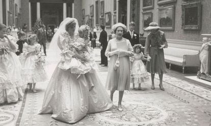 Diana de Gales camina con una de las damas de honor en brazos junto a la reina Isabel II.