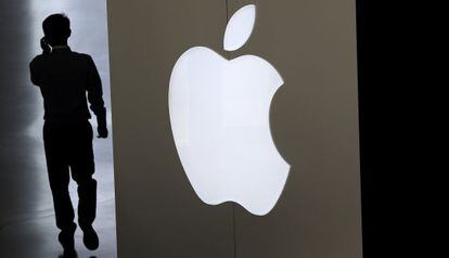 Un hombre habla por tel&eacute;fono junto a un logotipo de Apple