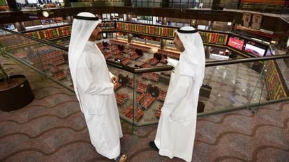 Dos hombres siguen el desempeño de la Bolsa de Kuwait.