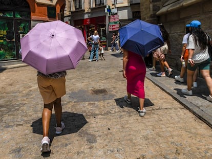 Dos personas pasean protegiéndose del calor con paraguas en una calle de Toledo, donde sigue este martes en alerta naranja por altas temperaturas.