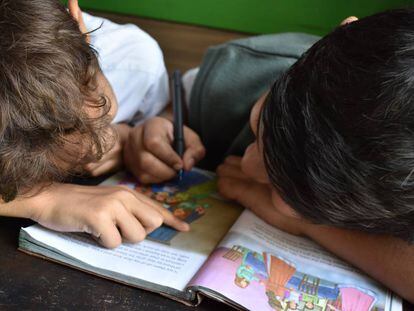 Dos niños leen un libro. 