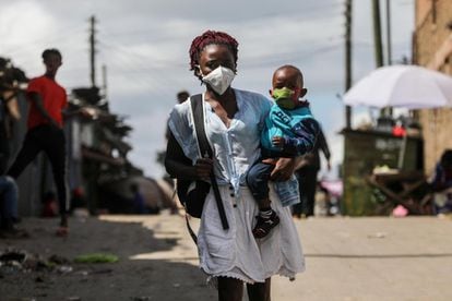 Una mujer de Kenia junto con su hijo. Ambos usan mascarillas durante el domingo de Pascua. La mayor parte de las iglesias han permanecido cerradas, lo que obligó a la mayoría de los fieles a quedarse en los barrios marginales de Mathare, en Nairobi (Kenia).
