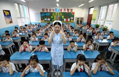 Una trabajadora de un hospital enseña a alumnos de primaria a realizar ejercicios para cuidar los ojos, en una escuela de Handan (China).