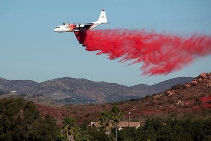 Un avión aprovecha el viento y deja caer una sustancia retardadora de incendios sobre Bonsall, California, una de las áreas afectadas por las llamas.