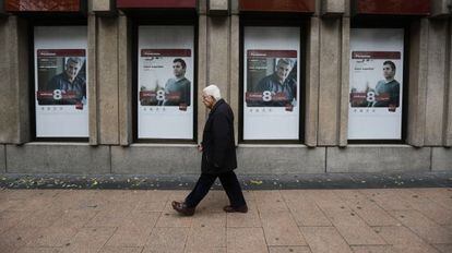 Un hombre pasa frente a anuncios de planes de pensiones de un banco