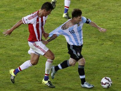 El mediocentro paraguayo V&iacute;ctor C&aacute;ceres intenta frenar a Messi agarr&aacute;ndole la camiseta durante el partido del s&aacute;bado.
