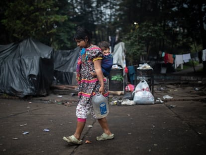 Una mujer indígena de la camunidad emberá, carga a su bebé mientras va a recoger agua, en el Parque Nacional de Bogotá, Colombia