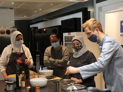 El chef Sebastian Simon prepara recetas con tres mujeres solicitantes de asilo en un taller organizado desde la ONG Accem en torno a las personas refugiadas y la cocina sostenible en Madrid.