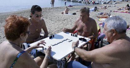 Varios jubilados juegan al dominó en una playa en Barcelona