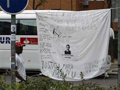 Un inmigrante pasa ante una sábana con pintadas alusivas a la muerte de Manu, en la calle de Villafuerte.