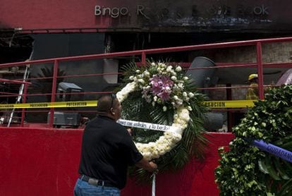 Un hombre coloca una corona de flores frente al lugar del incendio en el que murieron 53 personas