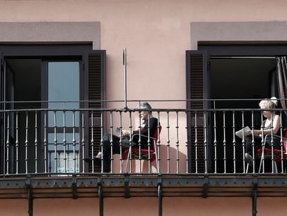 Dos personas leen en el balcón de su domicilio tras el estado de alarma decretado en España.