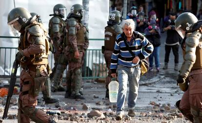 Un hombre camina entre policías antimotines durante las protestas registradas en Santiago el 18 de noviembre pasado.