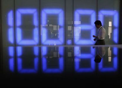 Un empleado de una firma de divisas de Tokio pasa ante un monitor que marca el cambio del yen con el d&oacute;lar. 