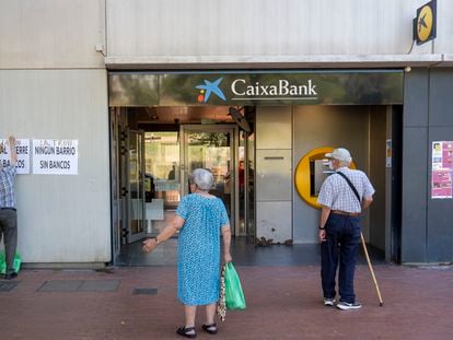Vecinos del barrio de la Trinitat Nova de Barcelona, ante una oficina bancaria a punto de cerrar.