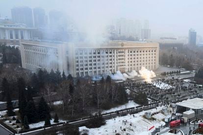 Columnas de humo se elevan ante un grupo de manifestantes junto al Ayuntamiento de Almaty (Kazajistán).