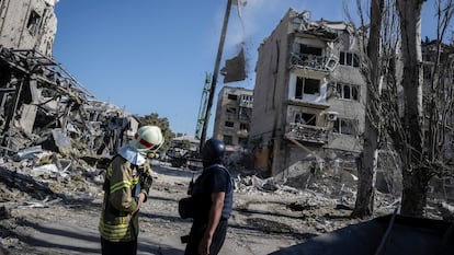 Dos rescatistas junto a un edificio destruido.