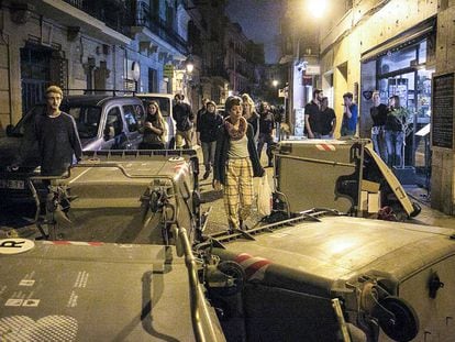 Veïns de Gràcia caminen entre els contenidors bolcats.