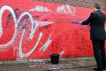 El primer ministro Tony Blair limpia un <i>graffiti</i> con agua a presión esta mañana durante una visita a Swindom, en el sur de Inglaterra.