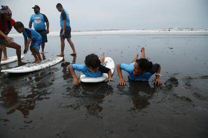 Las clases son gratuitas, y los únicos requisitos para los alumnos es que tengan entre 4 y 10 años y que estén dentro del nivel uno de autismo. En la imagen, una instructora enseña a un niño a bracear y patalear sobre la tabla de surf.