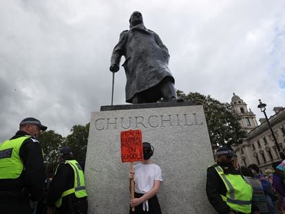 Agentes de policía custodian una estatua de Winston Churchill mientras un manifestante sostiene un cartel en el que se puede leer: "¡Enseñen la historia colonial en el colegio!", en Londres, el pasado 27 de junio.