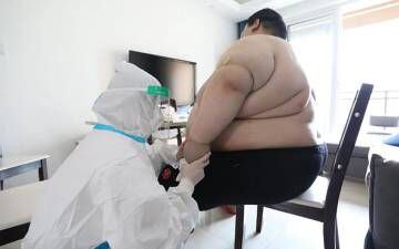 El paciente, atendido por un sanitario con un traje para evitar contagios.