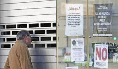 Un hombre observa el interior de una farmacia cerrada en seguimiento de la huelga indefinida de los farmacéuticos de la Comunitat Valenciana.