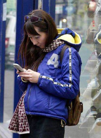 Una chica manda un mensaje SMS con su móvil.