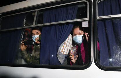 La llegada de 72 evacuados desde Wuhan, la ciudad china epicentro del coronavirus, ha provocado en Ucrania el miedo a que la enfermedad se expanda por el país. La difusión de una supuesta comunicación del Ministerio de Sanidad, en la que se afirmaba que había cinco casos de Covid-19 en el país, ha alentado el temor en la población. En la imagen, dos evacuados graban con sus móviles su llegada a Novye Sanzhari.