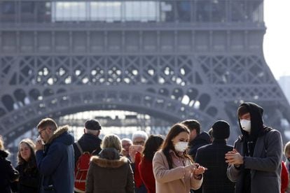 Dos turistas con mascarilla para evitar el coronavirus, ayer frente a la Torre Eiffel de París.