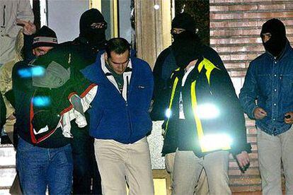 Agentes del Cuerpo Nacional de Policía trasladan a uno de los presuntos etarras detenidos ayer en Bilbao.