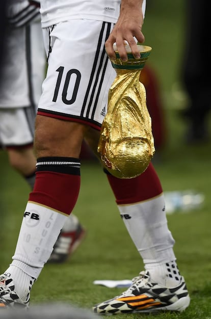 Lukas Podolski sostiene el trofeo del Mundial tras el partido