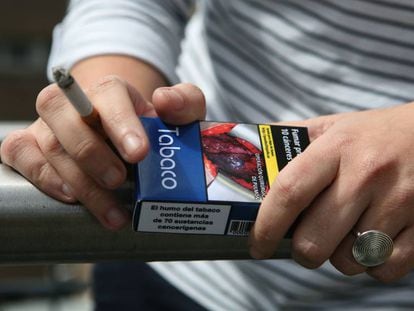 Una jove fumant amb un paquet de tabac a la mà