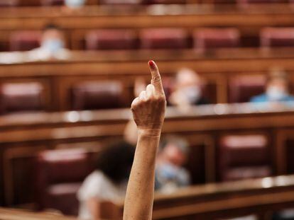 Una diputada indica, con su dedo, el sentido del voto en el Congreso de los Diputados.
