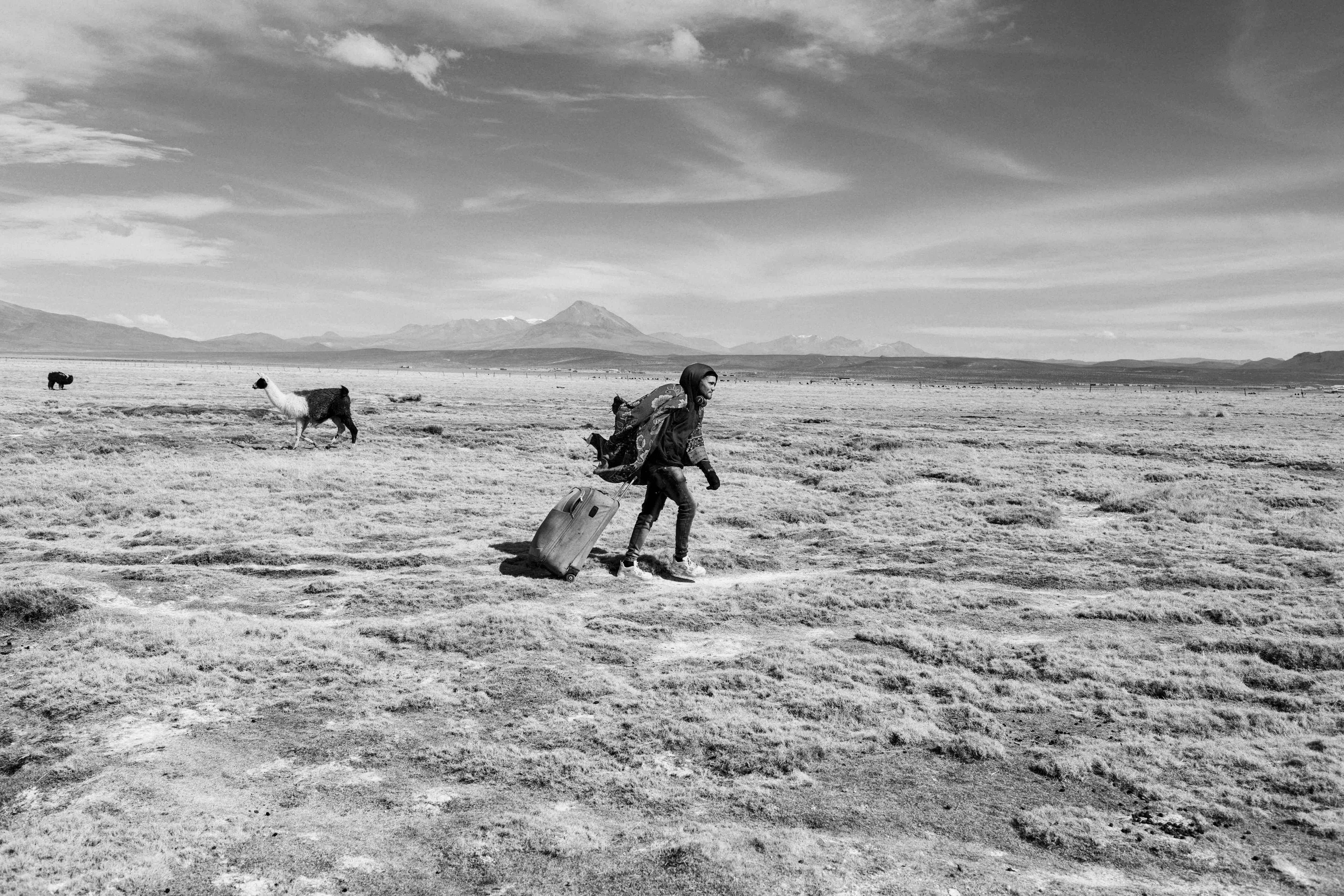 Luis Miguel, de 28 años, tira de una maleta con ruedas mientras cruza la meseta chileno-boliviana en Colchane, ciudad fronteriza con Chile, a 3650 metros sobre el nivel del mar, en julio de 2022.