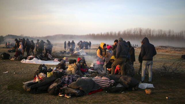 Unos migrantes se agolpan en la orilla del río Evros, este domingo cerca de Pazarkule (Turquía). En vídeo, un grupo de ciudadanos de Lesbos trata de impedir el desembarco de refugiados sirios.