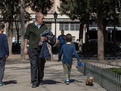 Dos niños y un hombre mayor pasean por un parque de Madrid.