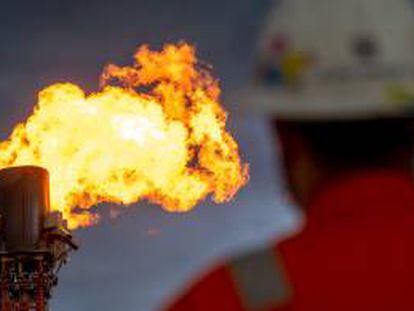 Un operario observa la quema de gas en una plataforma de extracción.