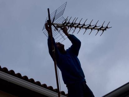 Un hombre ajusta la antena de televisión sobre el tejado en una localidad madrileña. 