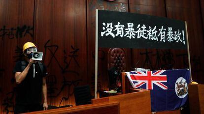 Un manifestante, junto a la bandera colonial, en el Parlamento de Hong Kong.