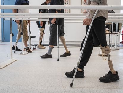 En la sala de rehabilitación de hombres, un grupo de sobrevivientes a la explosión de minas terrestres realizan ejercicios de movilidad con las prótesis para pies y piernas.